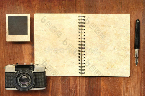木制背景上有钢笔、相框和照相机的空白笔记本