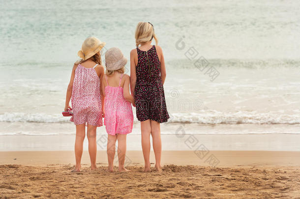 三个姐妹站在海边面对大海。