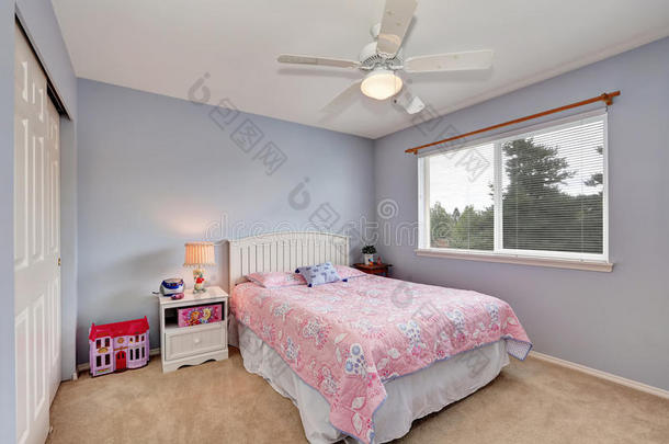 可爱的女孩的房间有粉红色的床上用品和柔软的薰衣草墙。