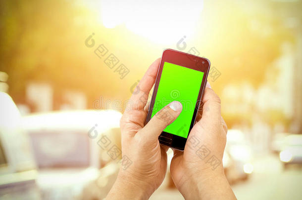 手动使用移动智能手机与色度键绿色屏幕在街道户外背景