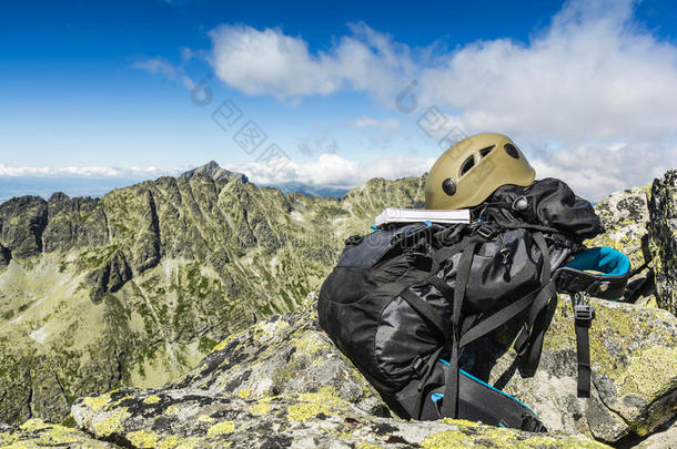 导游书，深色卡其色头盔和一个黑色背包在山上。