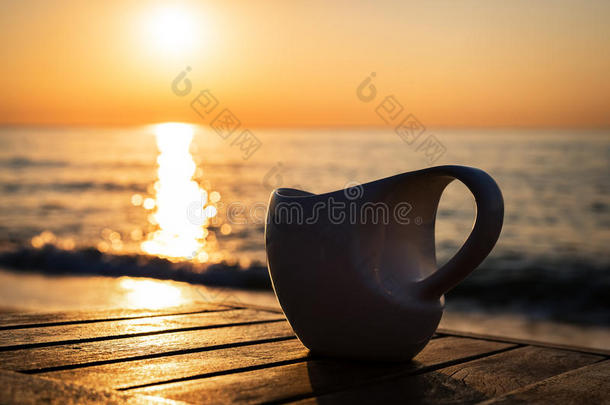 日落或日出海滩的木桌上的一杯咖啡