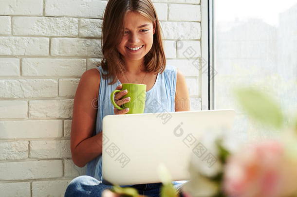 高兴的微笑女孩在她的<strong>笔记本</strong>电脑上工作，而坐在<strong>上面</strong>