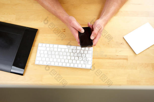 手拿手机按键盘放在桌子上