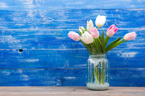 蓝色木桌背景上五颜六色的郁金香花。 复制空间