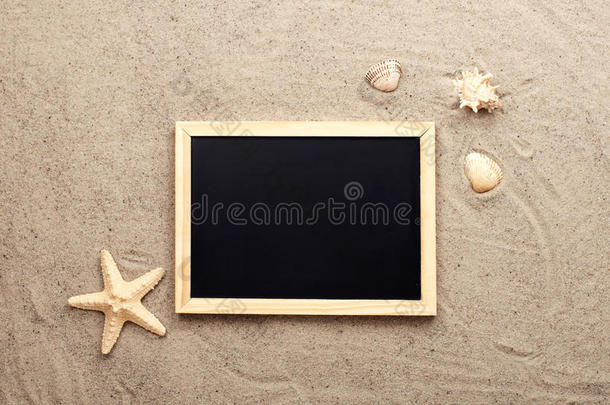 沙上的空白黑板，上面有贝壳和海星