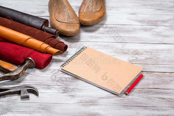 色彩鲜艳的皮革卷，工作工具，鞋持久，笔记本与铅笔在白色背景。 皮革工艺。