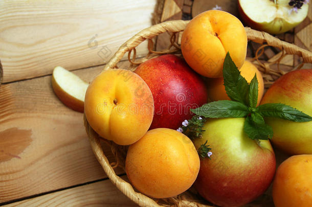 杏子和苹果放在木桌上的<strong>花篮</strong>里。