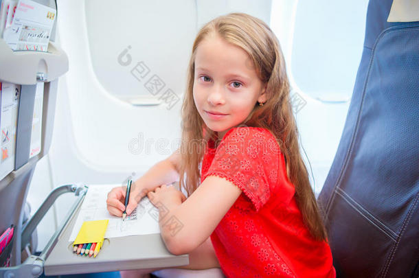 坐飞机旅行的可爱的小女孩。坐在飞机窗口附近用彩色铅笔画画的小孩