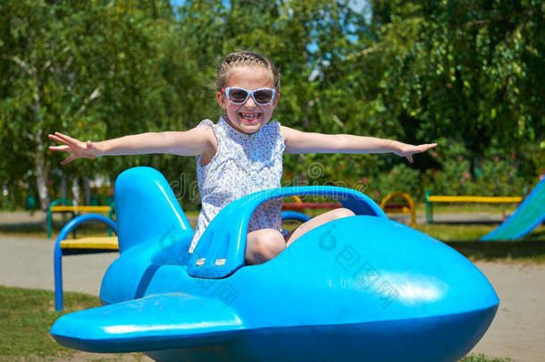 女孩在城市公园的<strong>蓝色</strong>飞机上飞翔，快乐的童年，暑假的概念