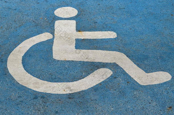 蓝色沥青上的残疾人或残疾人停车标志