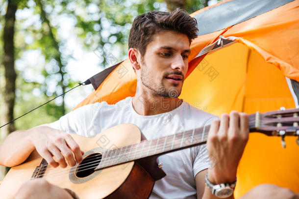 英俊的男人旅游帐篷里唱歌弹吉他