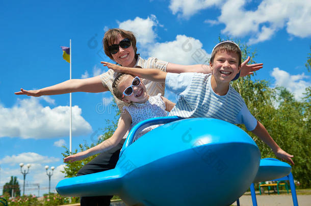孩子和女人在公园乘坐蓝色飞机，快乐的家庭享受乐趣，暑假的概念