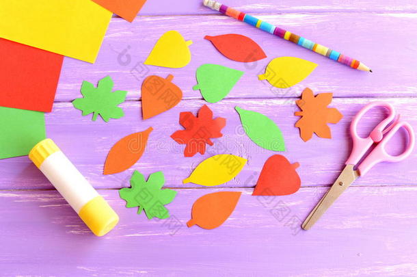 用彩色纸、剪刀、胶棒、铅笔、紫色木底纸剪成的五颜六色的叶子。 上面的风景