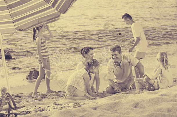 家庭有四个孩子在海滩上放松
