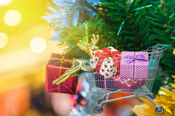 圣诞礼物和礼物在购物车与圣诞装饰品和圣诞树背景。