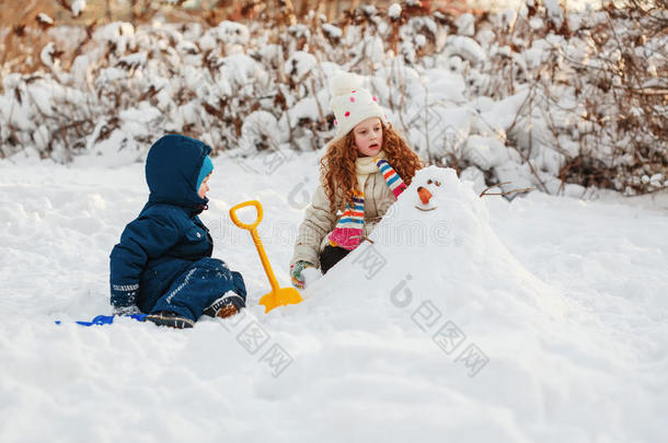 孩子们在公园里冬天散步时和雪人玩耍。