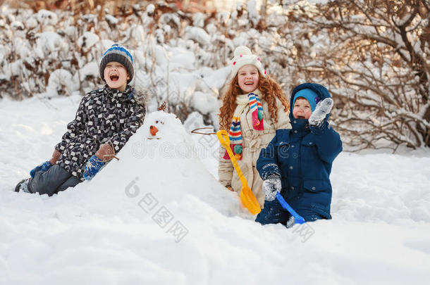 孩子们在公园里冬天散步时和雪人玩耍。