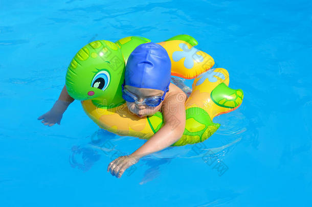 一个小孩子在游泳池里游泳，护目镜，游泳帽。