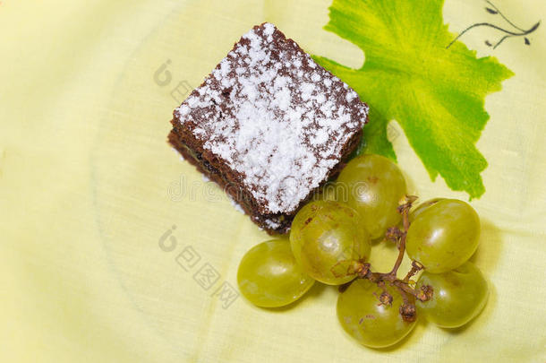 黄色桌布上有冰糖和葡萄的巧克力海绵蛋糕