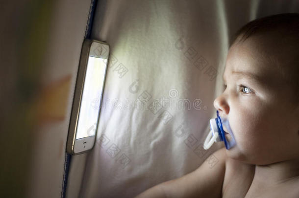 婴儿在婴儿床上用手机看摇篮曲动画片