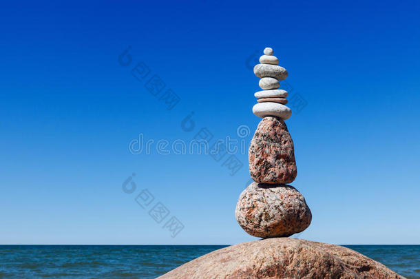 平衡并使石头紧贴大海。 蓝天背景上的摇滚禅宗。