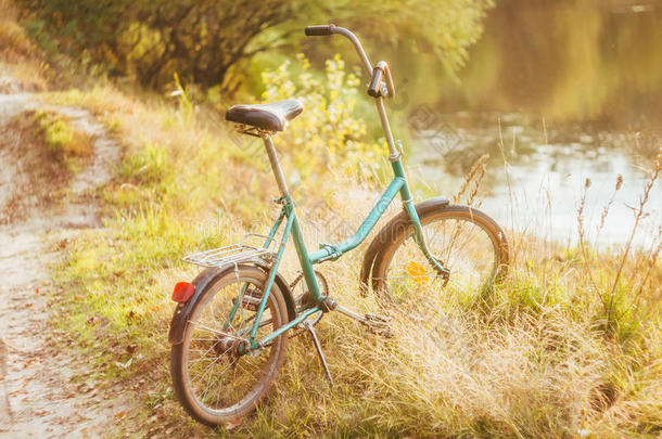 绿色自行车站在绿色的夏季或秋季草地上，在干燥的黄色草地上