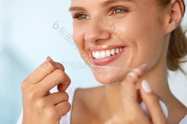 牙科卫生。 美丽的女人用牙线清洁健康的白牙
