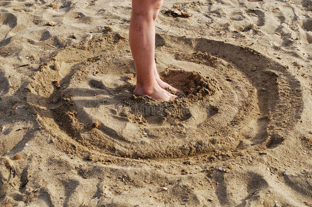 圆圈画在沙子上，脚在中间