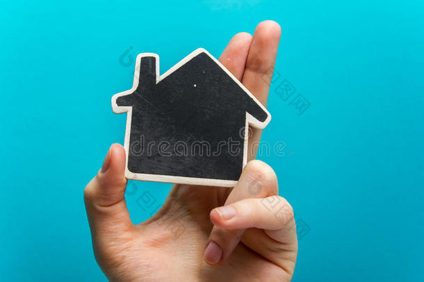 手拿着<strong>蓝色背景</strong>上的白纸屋人物。 <strong>房地产</strong>概念。 复制空间顶部视图。