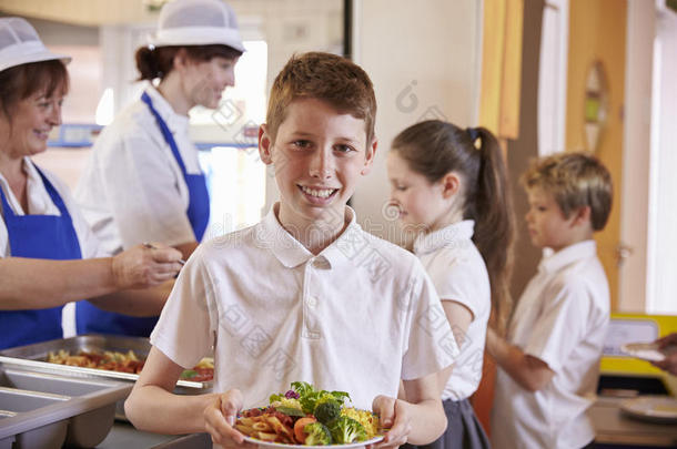 高加索小学生在学校自助餐厅拿着一盘食物