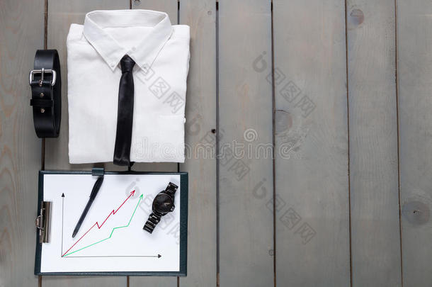 商人，灰色木制背景的工作装备。 白色衬衫，黑色领带，腰带，普朗切特。 回到过去。 一组男人