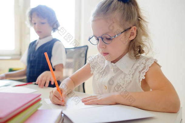 戴眼镜的可爱的小女孩，勤奋地写在一本<strong>抄</strong>本上的东西。
