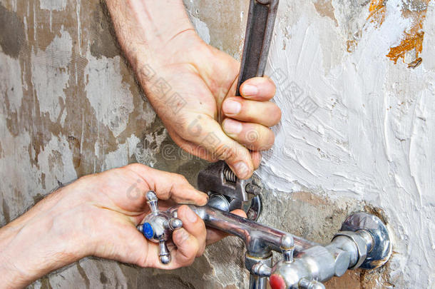 拆卸旧故障水龙头，用扳手修理水管工的手。