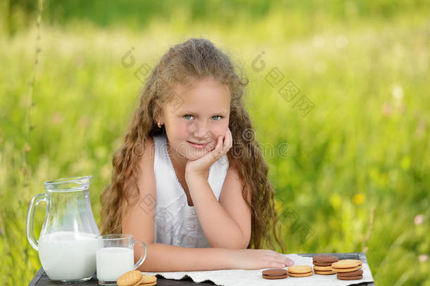 可爱的微笑女孩在户外夏天吃早餐喝牛奶