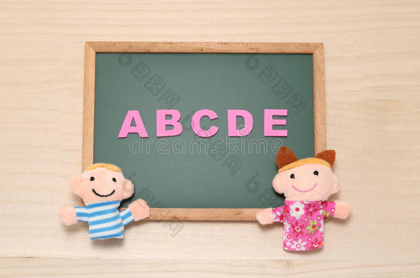 字母表字母abcde和儿童玩偶在黑板上。英语教育理念。