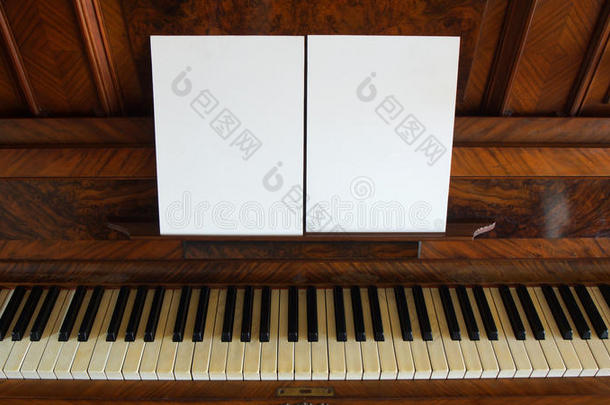 一架古董钢琴的正面视图，键盘打开，两张白纸支持音符