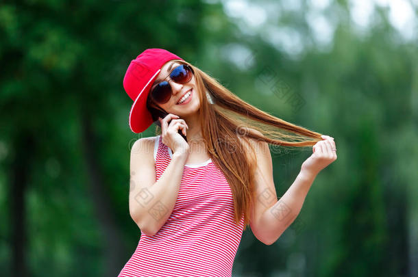 时尚城市肖像时尚时髦的女人说话<strong>手机</strong>，红色条纹连衣裙，红色帽子和运动鞋，<strong>化妆</strong>