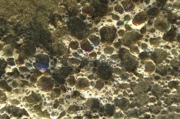 五颜六色的海浪泡沫泡在沙滩上。