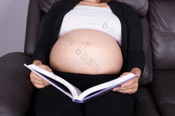 关闭躺在沙发上的孕妇和阅<strong>读书籍</strong>