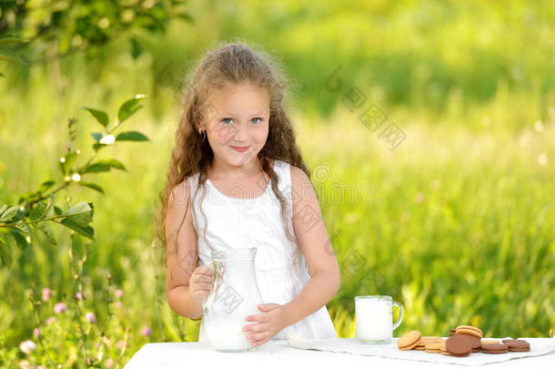 可爱的微笑女孩在户外夏天吃早餐喝牛奶