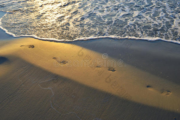 夏天日落时沙滩上的脚印