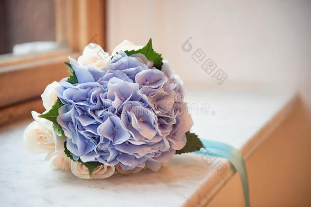 一束白色和蓝色的绣球花，用丝带绑在窗台上