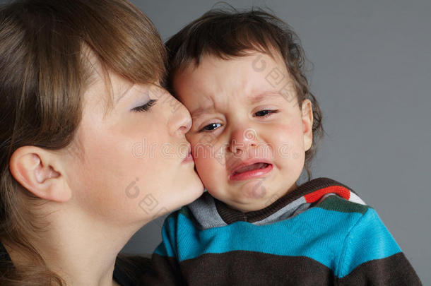 美丽的母亲亲吻她哭泣的儿子