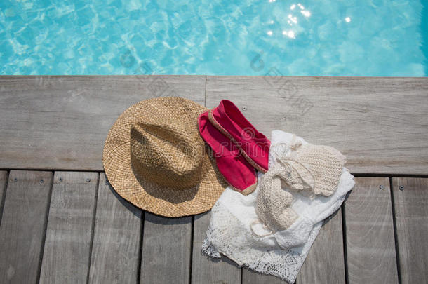可爱的粉红色鞋子和夏天的帽子在游泳池旁边