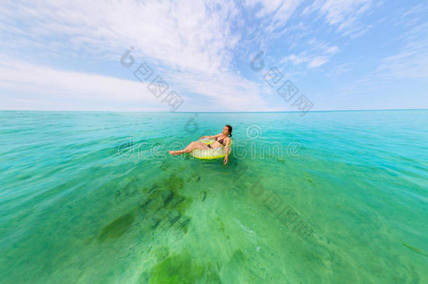 女孩穿着充气戒指漂浮在蔚蓝的大海里