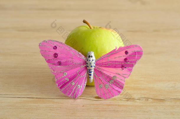 一个绿色的苹果用粉红色的蝴蝶展示