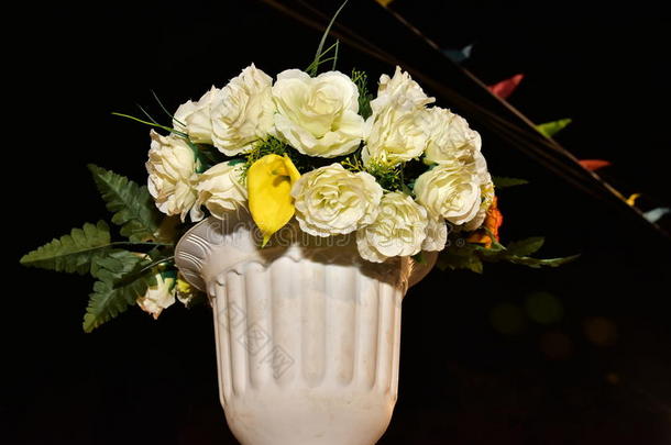 人工白色玫瑰在花瓶和塑料盒子在天空在晚上