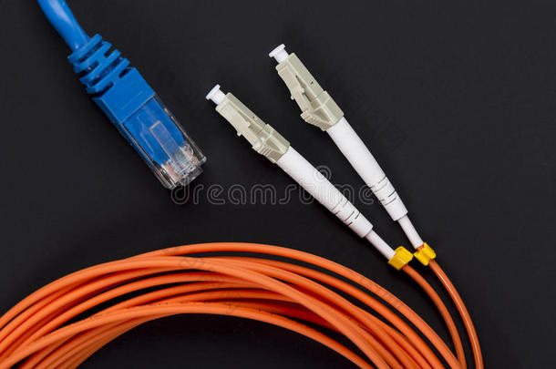 蓝色双绞线贴片线与光纤橙色电缆在黑暗的背景