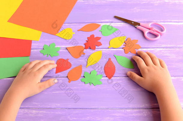 孩子用彩色纸剪出秋天的叶子。 做秋纸工艺品的孩子。 学前教育艺术和工艺